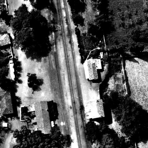 Full-resolution detail of the 1941 aerial photo: platform and tracks with two detached tiled houses on one side and a long tiled building with walled courtyard and a small white building on the other.