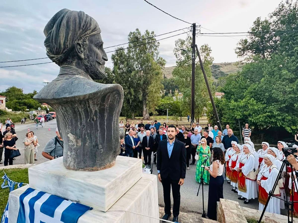 The bronze bust of General Makriyannis with a Greek flag, and behind it the people gathered for the bicentenary commemoration, 15 June 2025