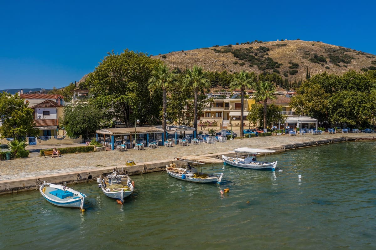 Small fishing boats in the harbour with the waterfront and Pontinos hill behind