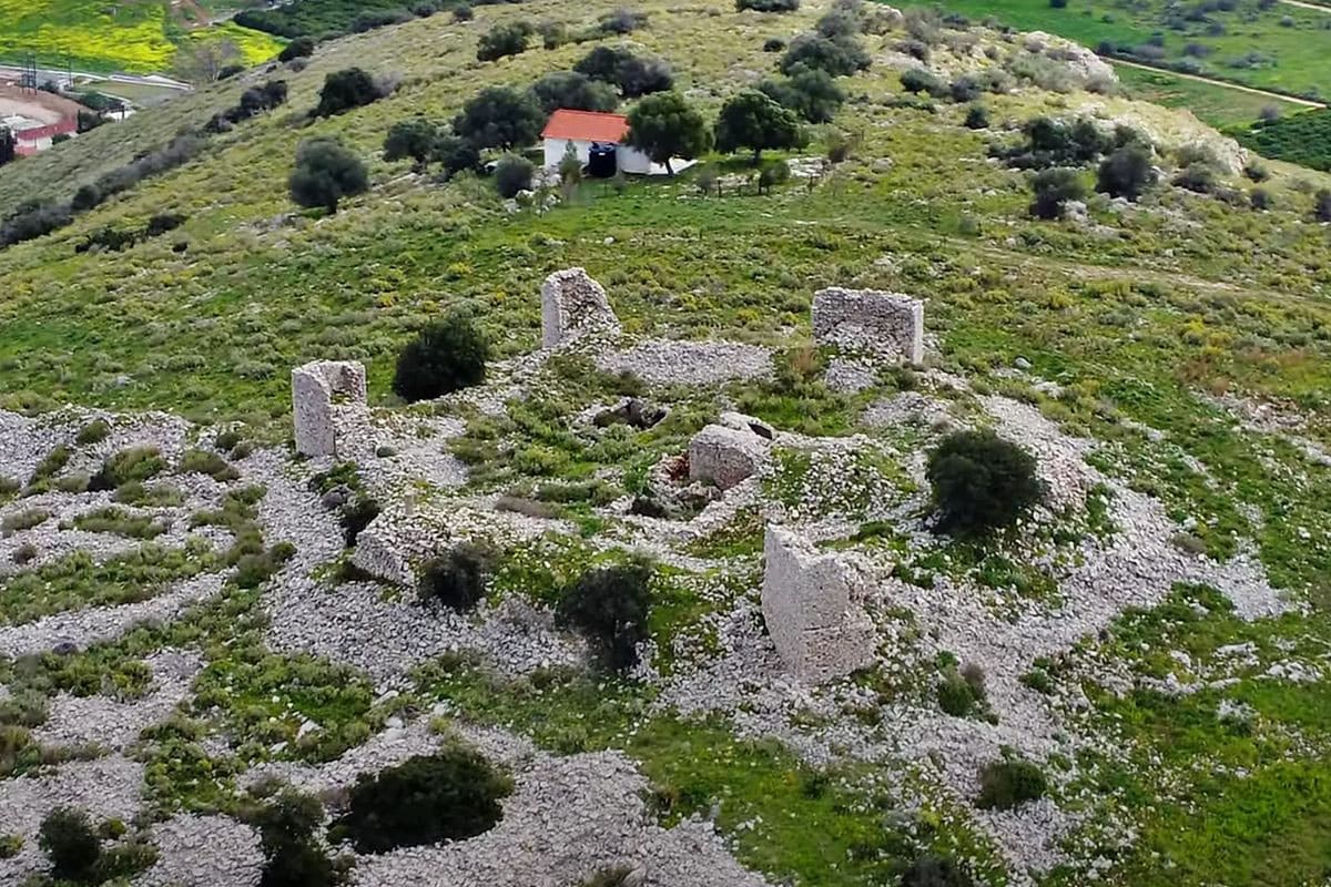 Ruined castle walls on Pontinos hill seen from above, with a small white chapel