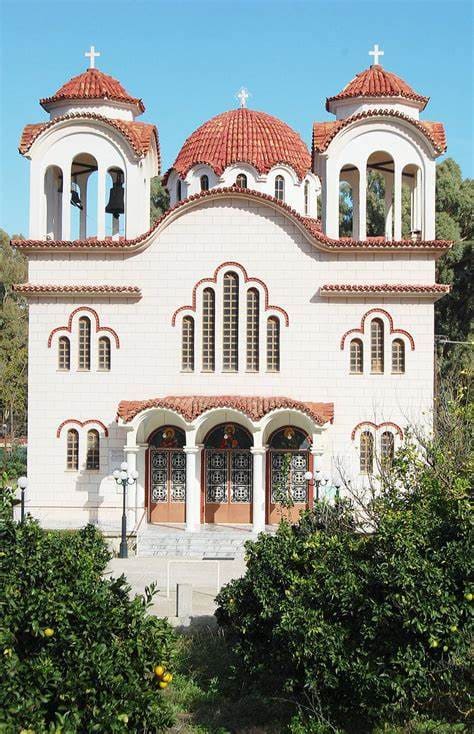 The white church of the Holy Apostles in Myloi with two bell towers and red domes