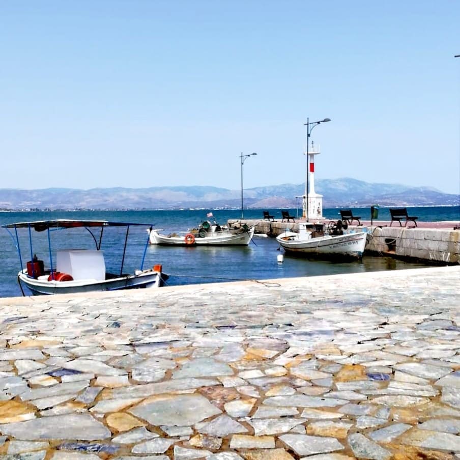 Small fishing boats moored at the stone-paved quay of Myloi