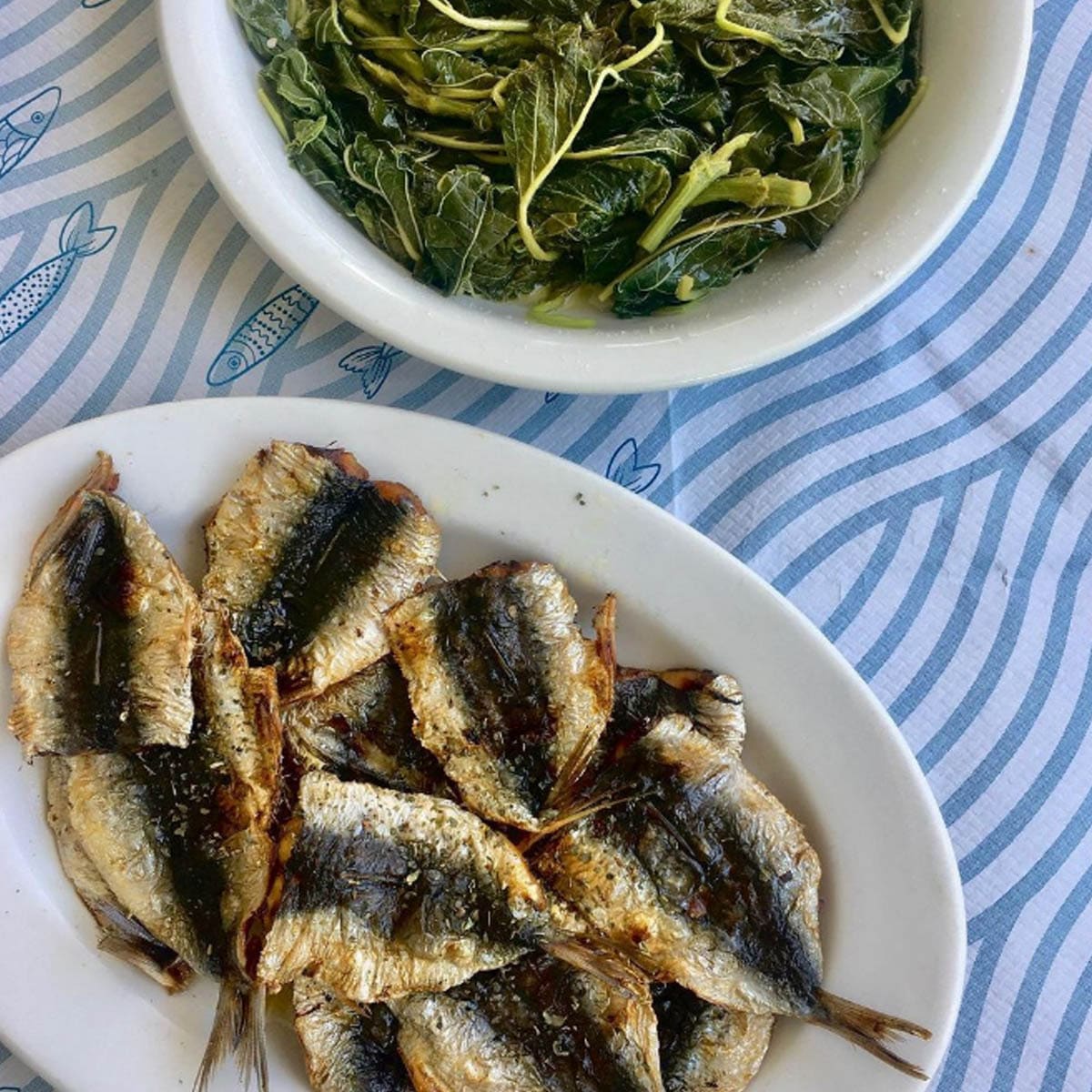 Fried small fish with a bowl of boiled wild greens