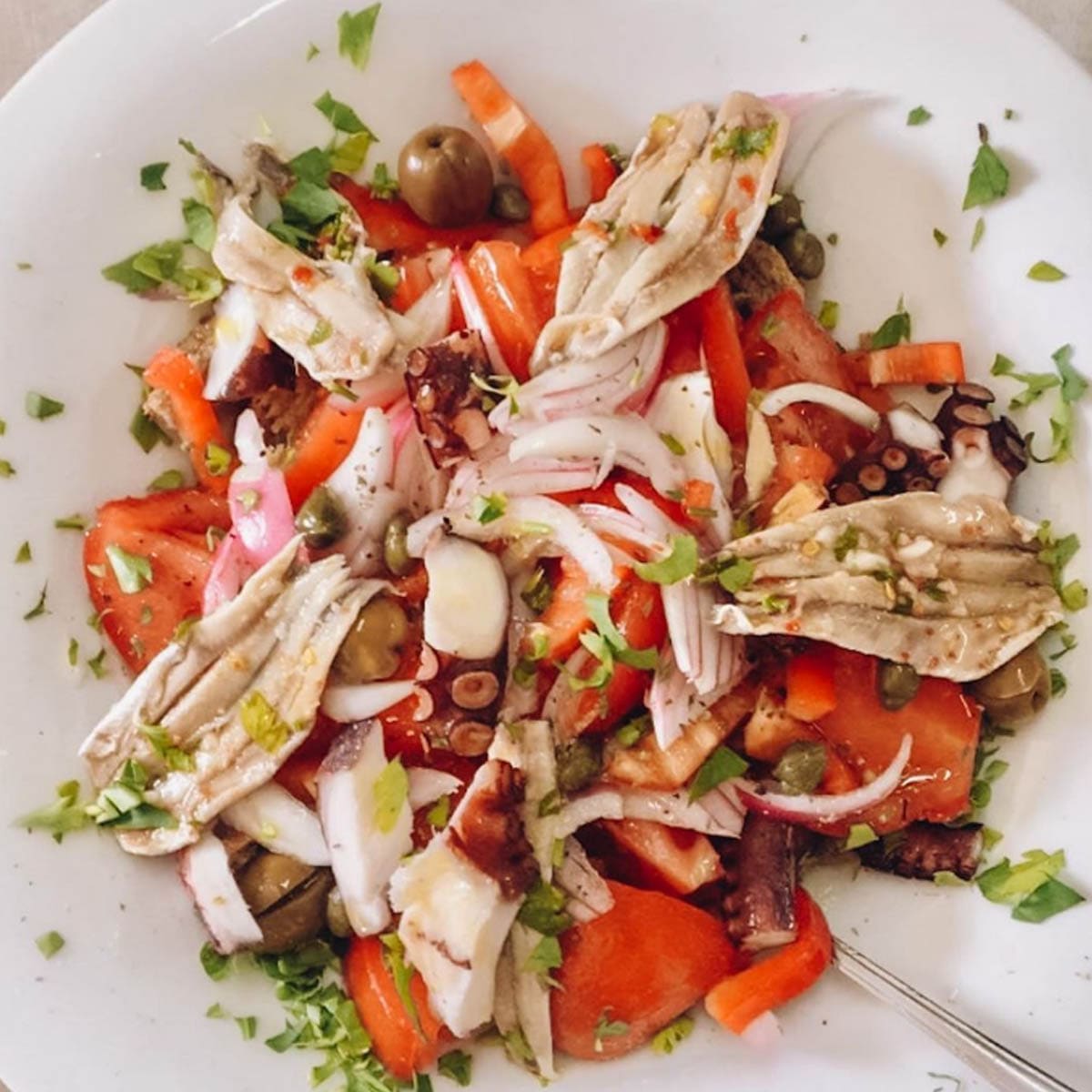Octopus salad with tomato, onion and fresh herbs
