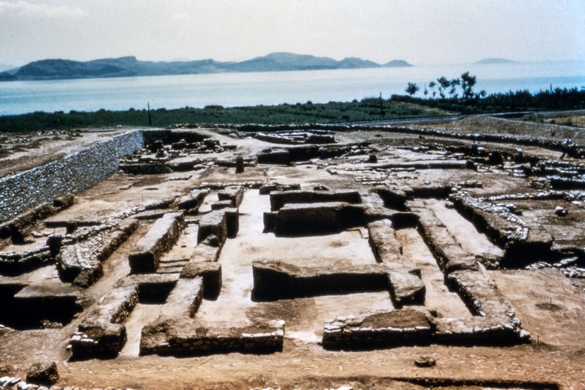 The excavated stone walls of prehistoric Lerna in the 1950s, laid out in rectangles, with the Argolic Gulf and the mountains beyond
