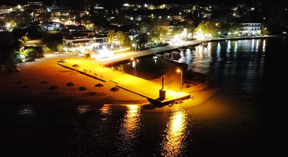The illuminated pier and waterfront of Myloi at night, seen from above