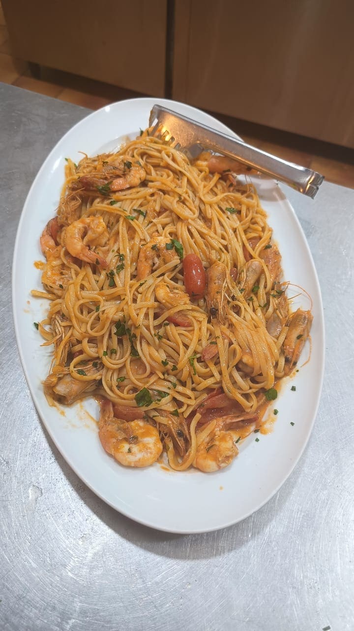 A large platter of spaghetti with shrimp and tomato, ready to serve