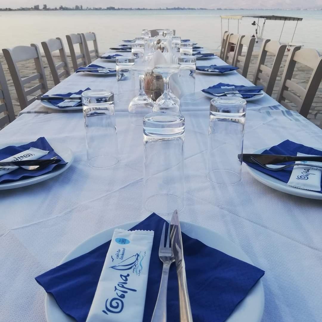 Long table set by the sea with Ostria napkins and glasses