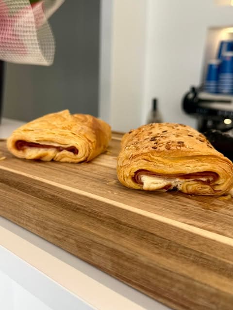 Two puff-pastry pies with ham and cheese on a wooden board