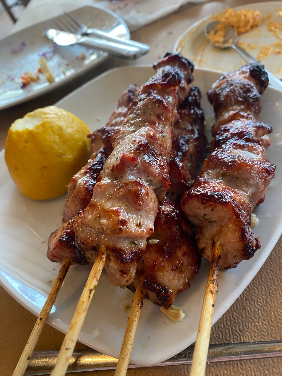 Three grilled pork souvlaki skewers with a lemon half