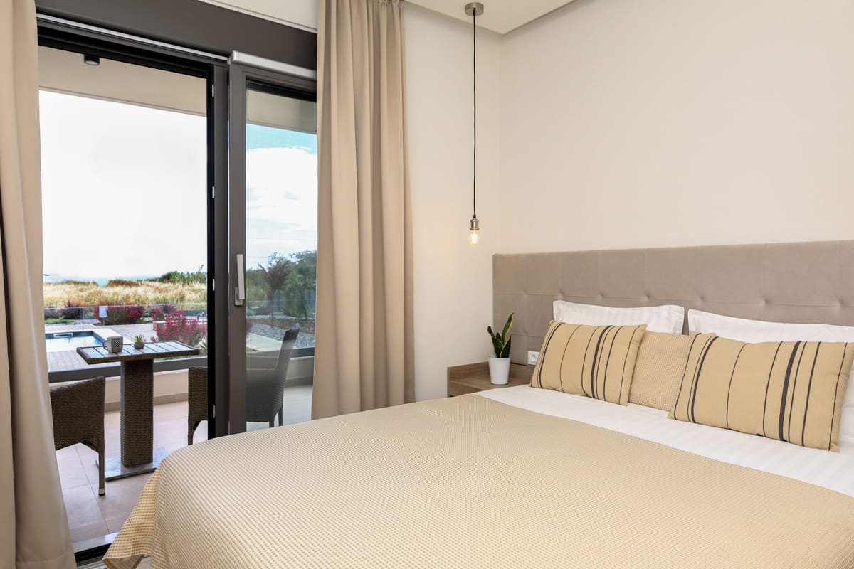 Double bedroom in soft beige tones with the glass door open to the balcony and the view