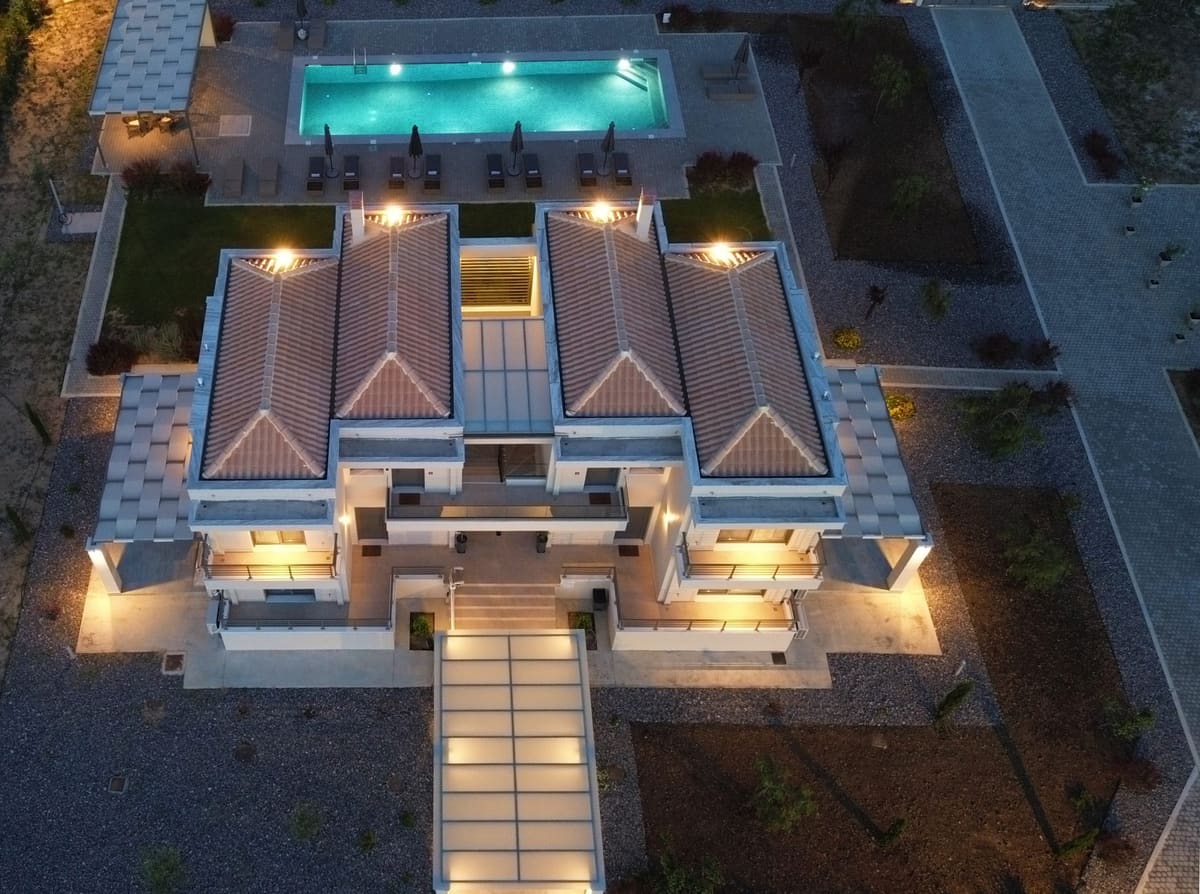 The estate from the air at night: the lit buildings, the illuminated pool and the garden paths