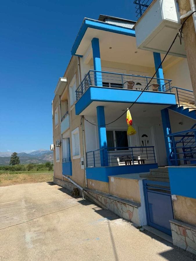 The house with blue balcony railings and columns under a clear blue sky