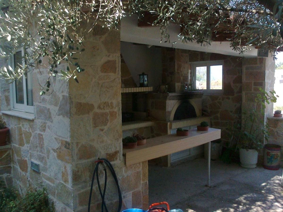 Stone-built barbecue and outdoor kitchen under an olive tree in the courtyard