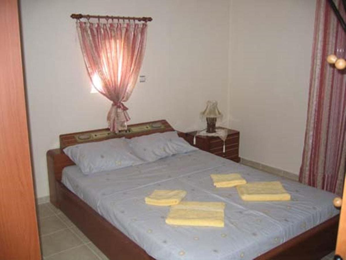 Bedroom with a double bed, folded yellow towels, bedside lamps and a curtained window