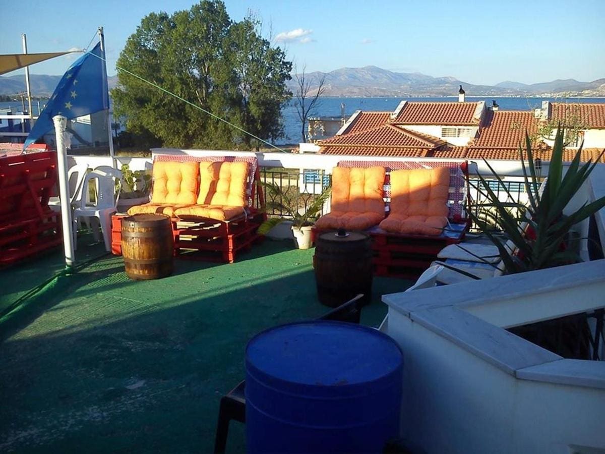 Roof terrace with colourful cushioned seats and barrels as tables, looking over the rooftops to the gulf and mountains