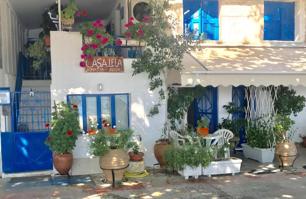 Whitewashed entrance of Casa Lela with flower pots and blue shutters