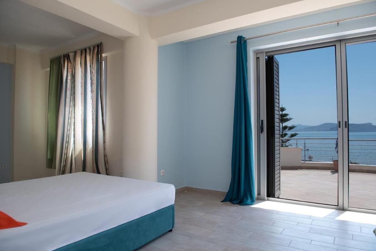 Bedroom with a double bed and the glass balcony door open to the terrace and the sea