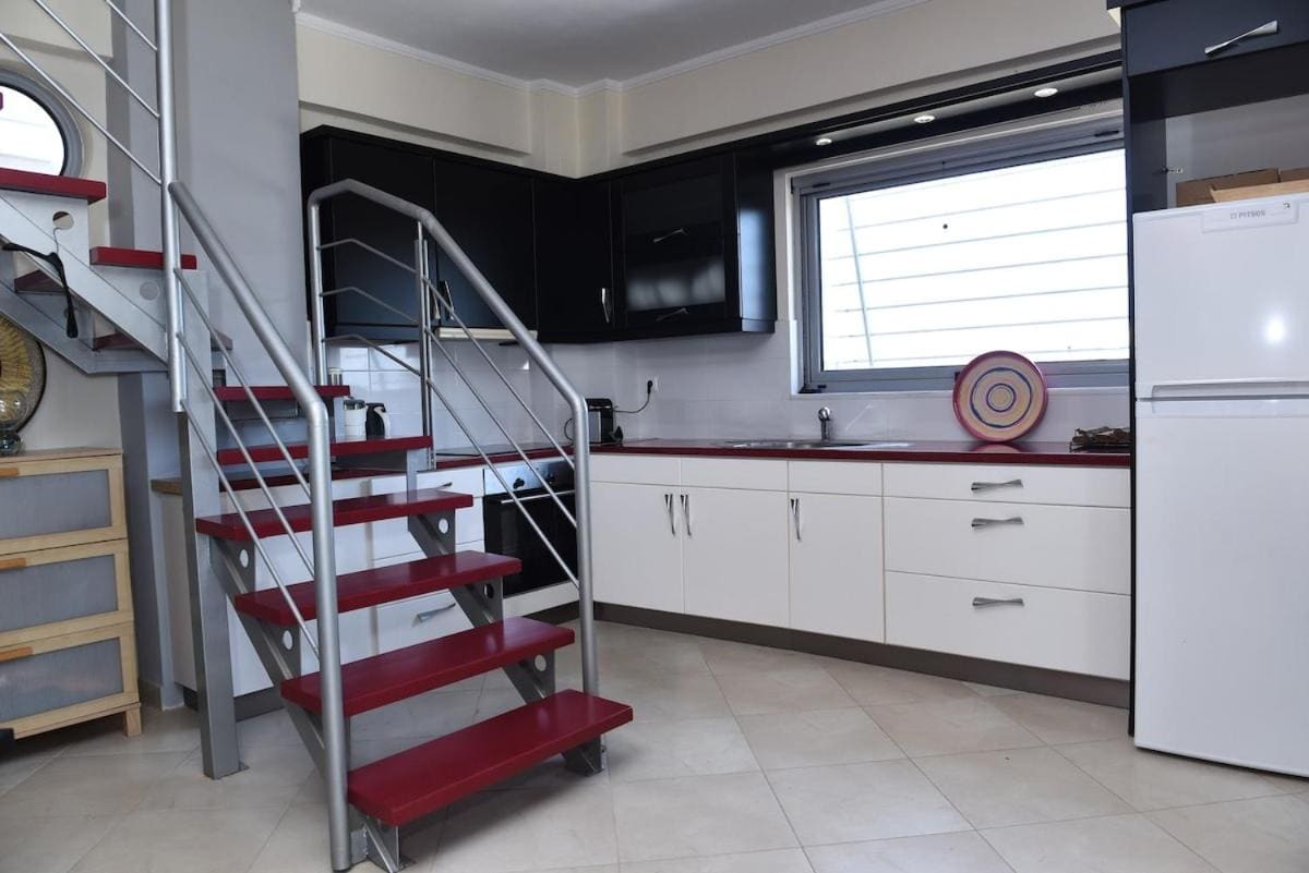 Kitchen with black and white cabinets, a fridge and oven, and a red spiral staircase
