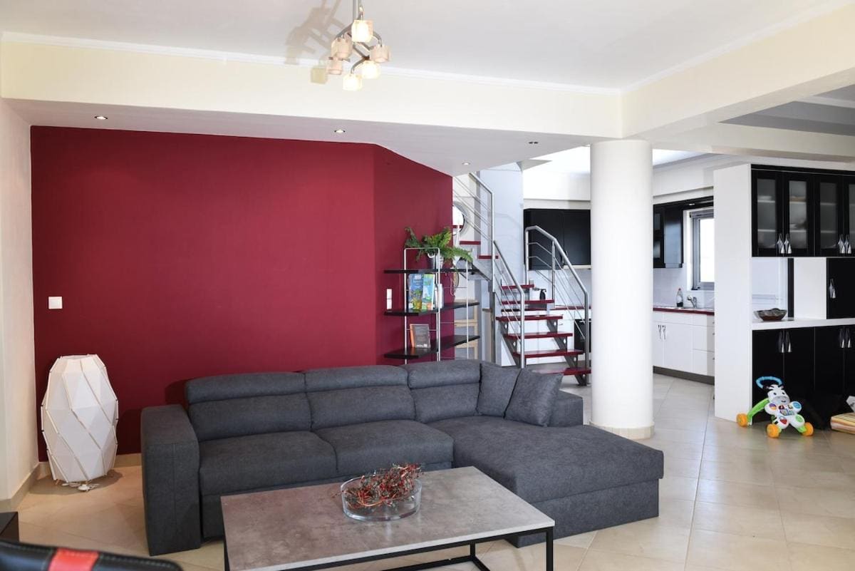 Living room with a grey corner sofa, a red feature wall, a coffee table and stairs to the upper floor