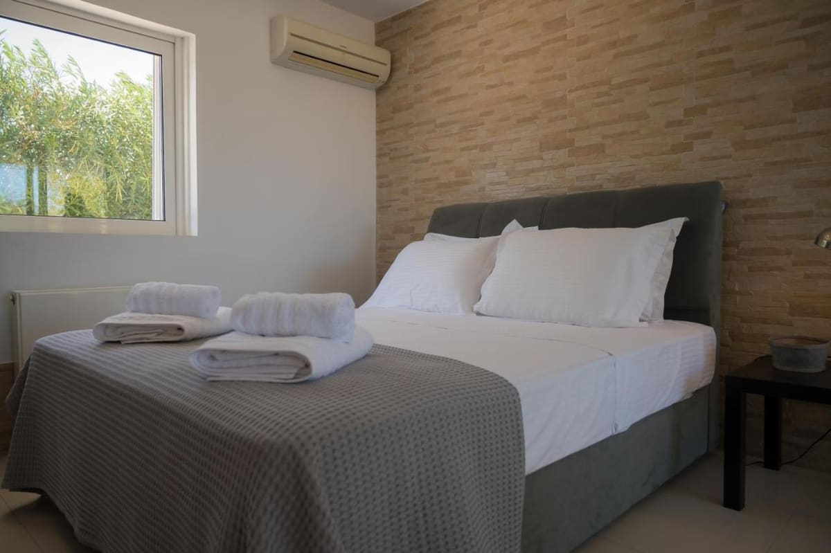 Double bedroom with a stone-clad feature wall, folded towels and a window to the garden