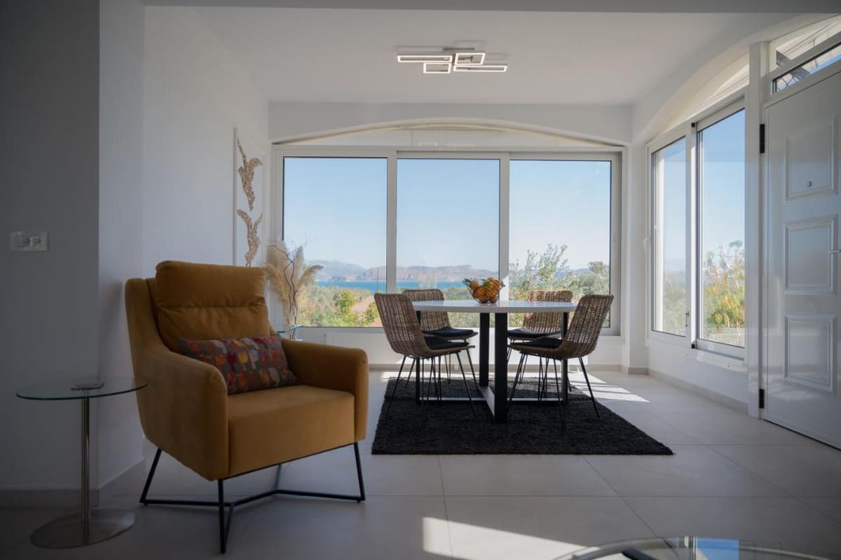 Bright living room with a yellow armchair, a dining table and large windows on two sides