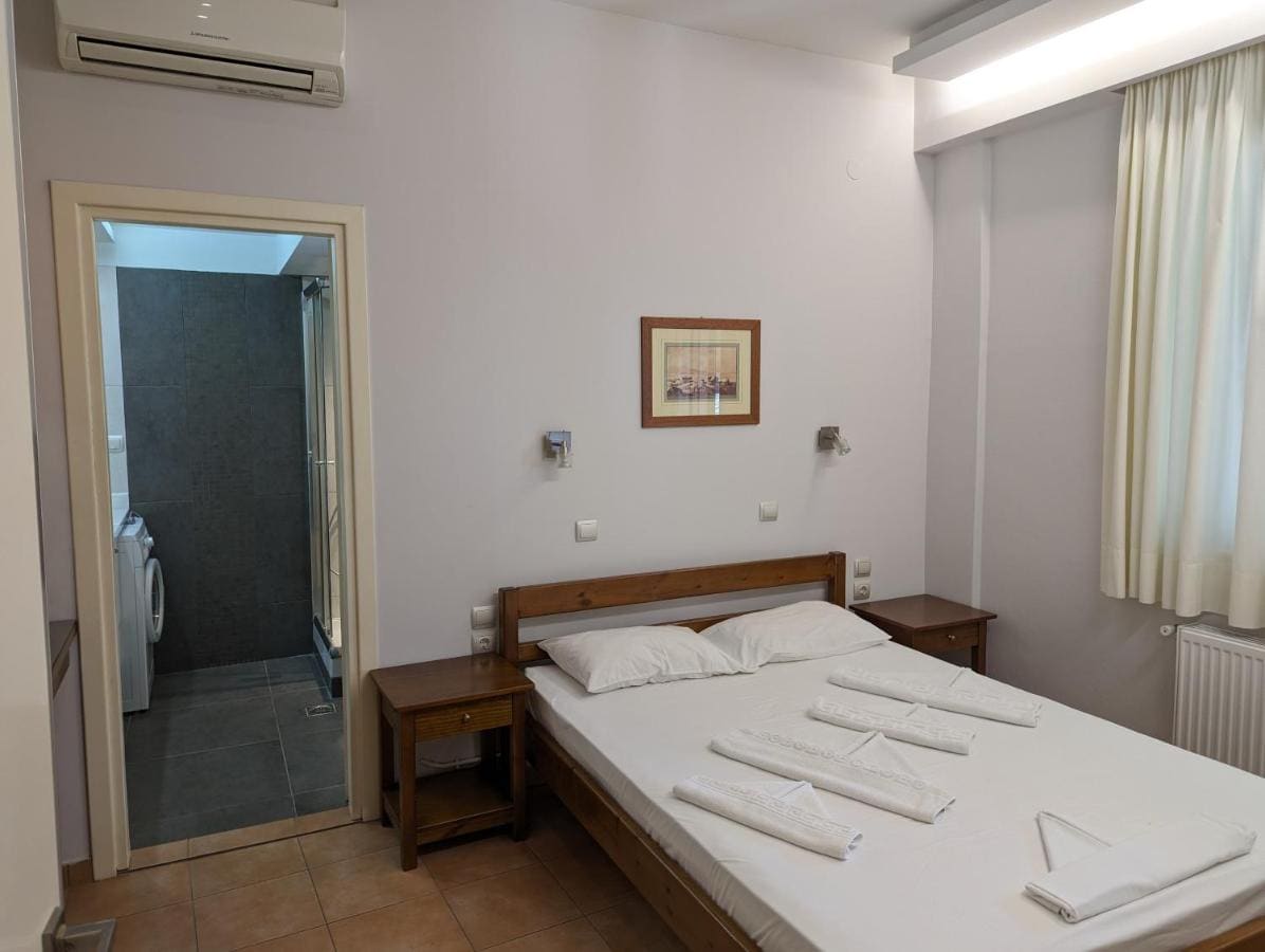 Double room with a wooden bed, folded towels, air conditioning and the bathroom door open