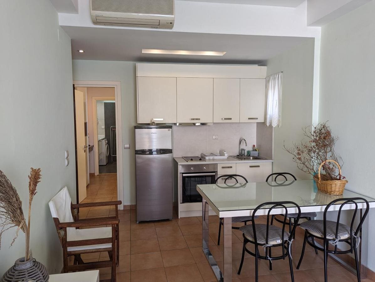 Apartment with a white kitchen, an oven, a fridge and a glass dining table with chairs