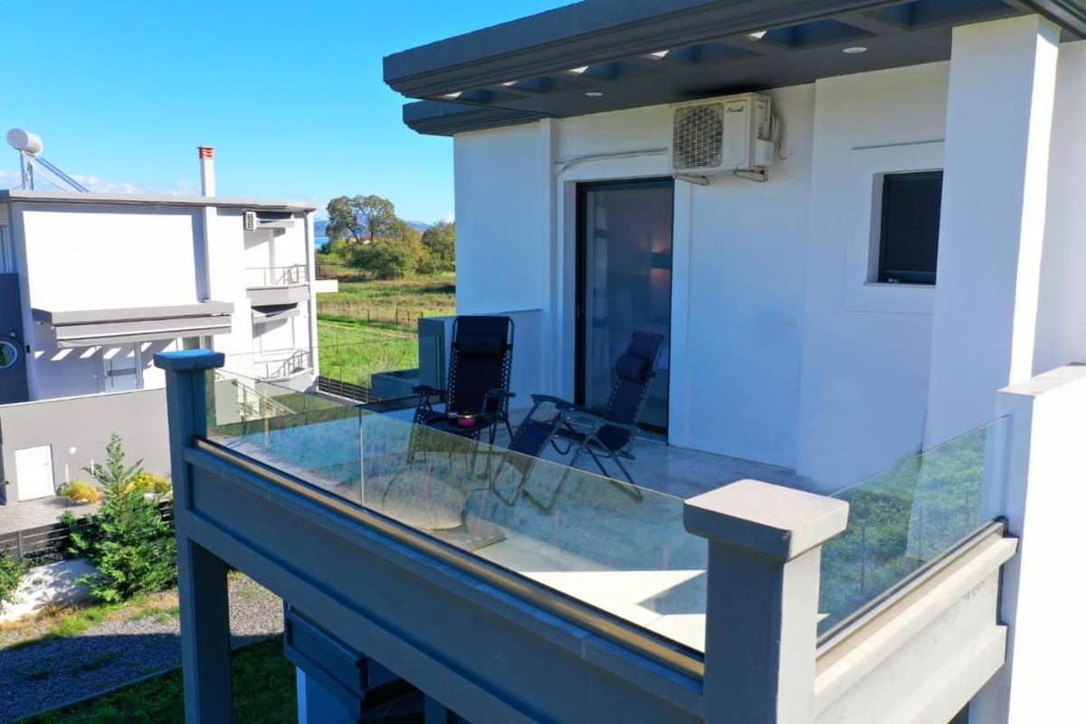 Upper-floor balcony with a glass railing and sun loungers, above the garden