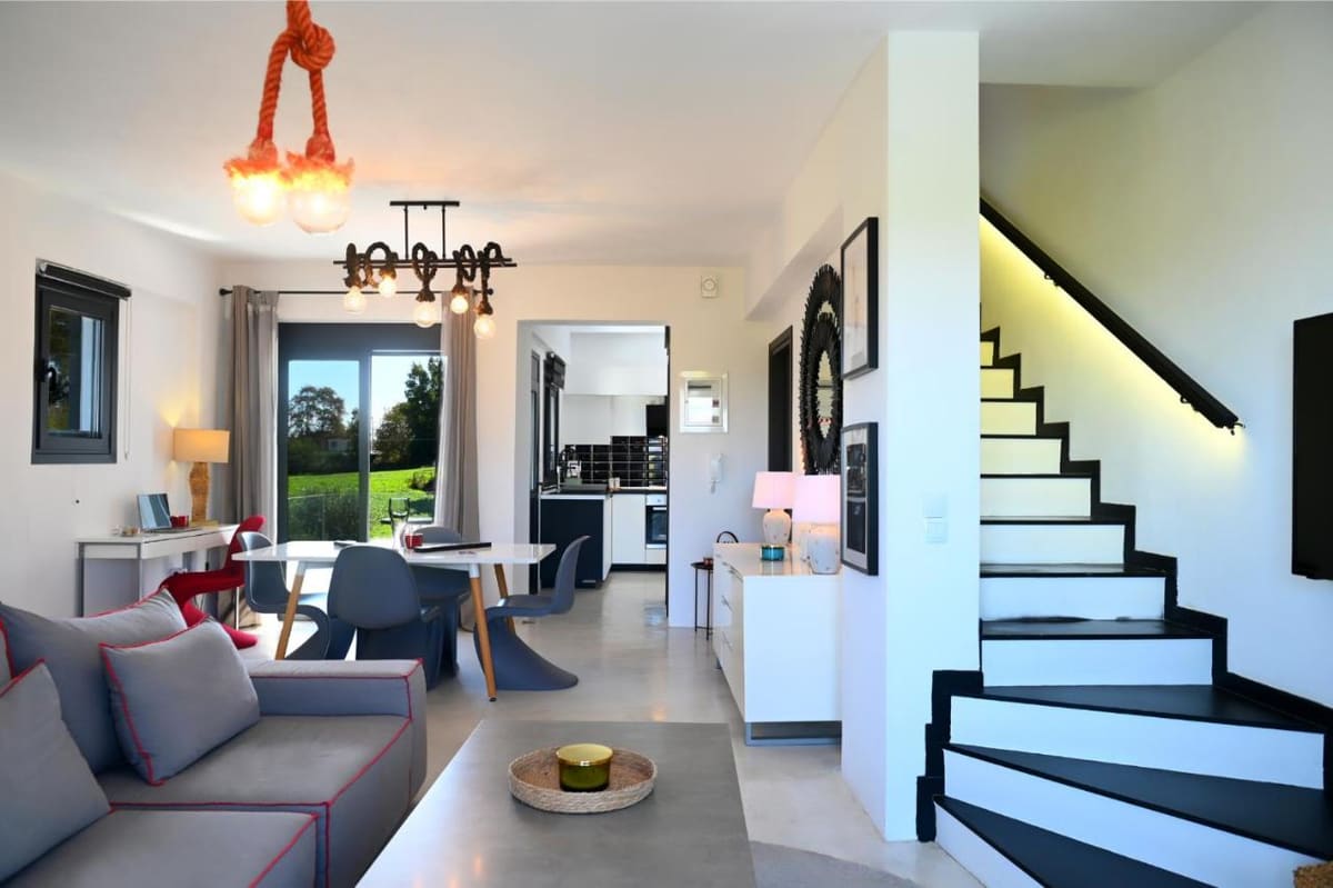 Open-plan ground floor with a sitting area, a dining table, the kitchen beyond and a staircase to the upper floor