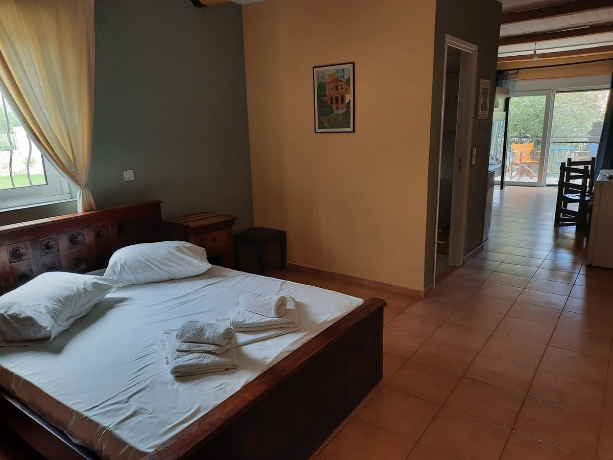 Apartment with a double bed, wooden beams and a balcony door open to the green garden