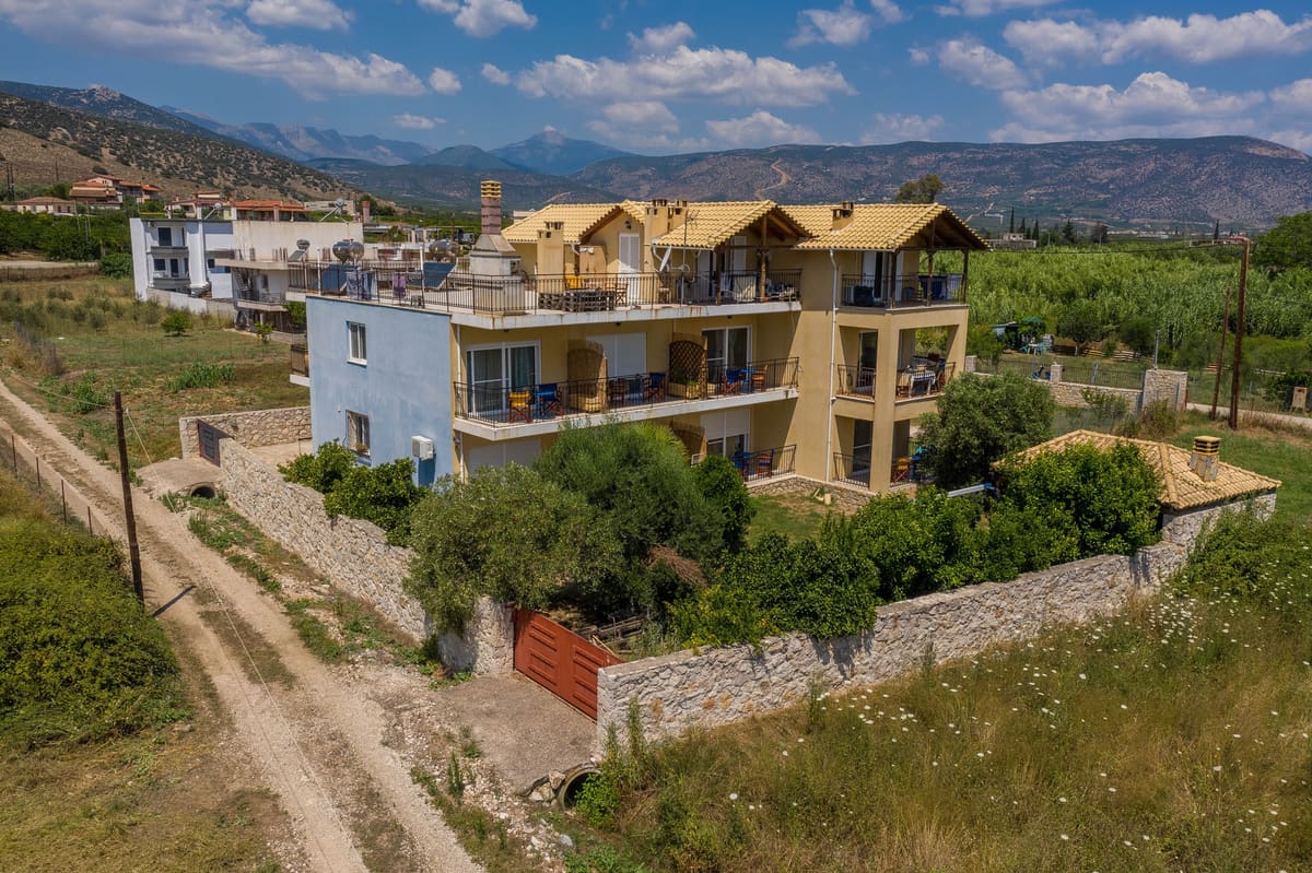 The Myloi Inn among fields with the mountains behind