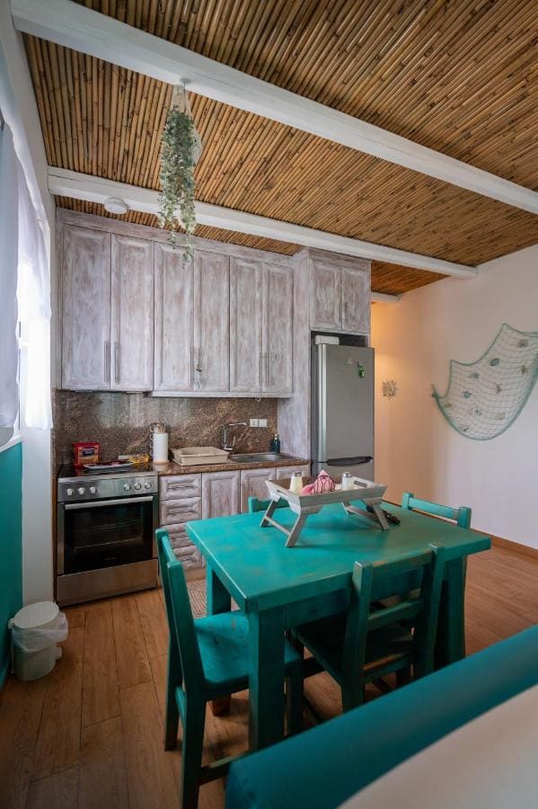 Kitchen with whitewashed wooden cabinets, an oven, a fridge and a turquoise dining table
