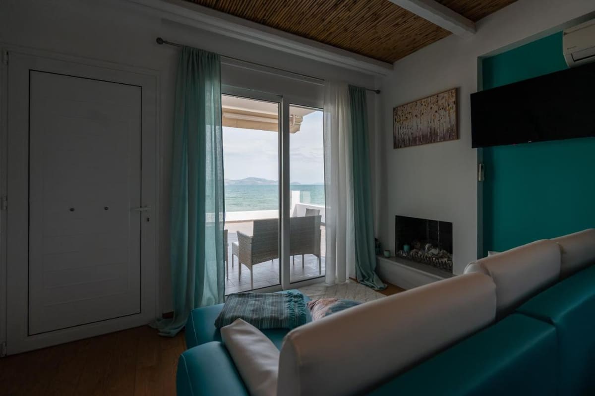 Sofa and fireplace in the living room, with the sliding door open to the terrace and the sea