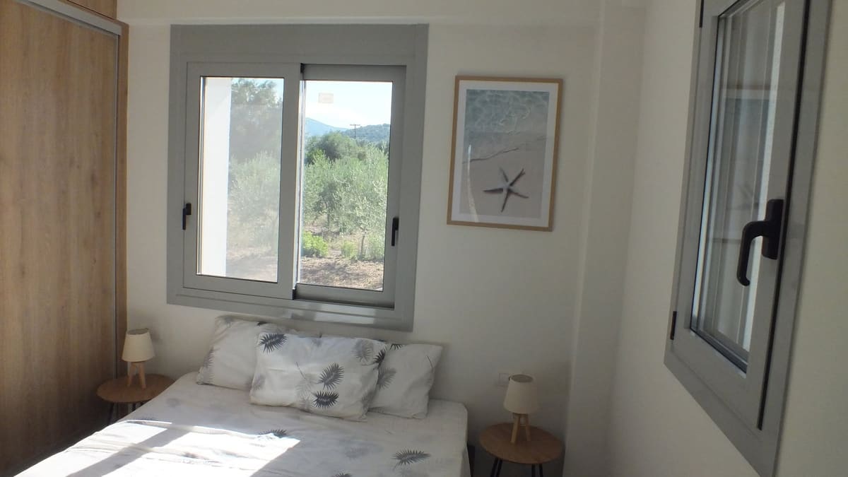 Double bed under a window looking out on olive trees