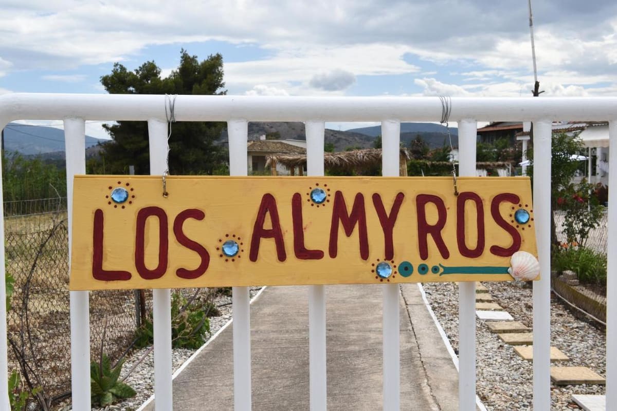 Hand-painted yellow 'Los Almyros' sign on the white garden gate