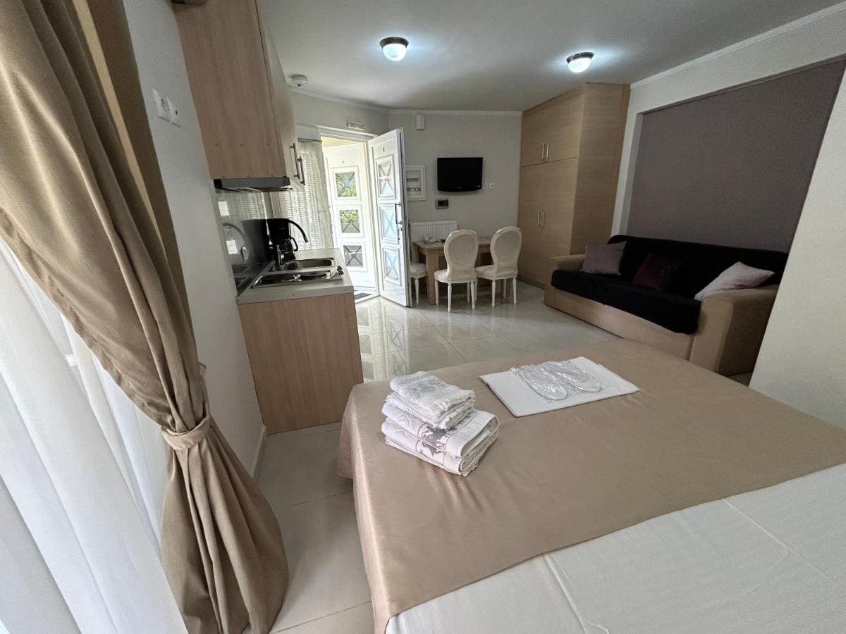 Apartment with a double bed and folded towels, a kitchen corner, a dining table and a door to the balcony