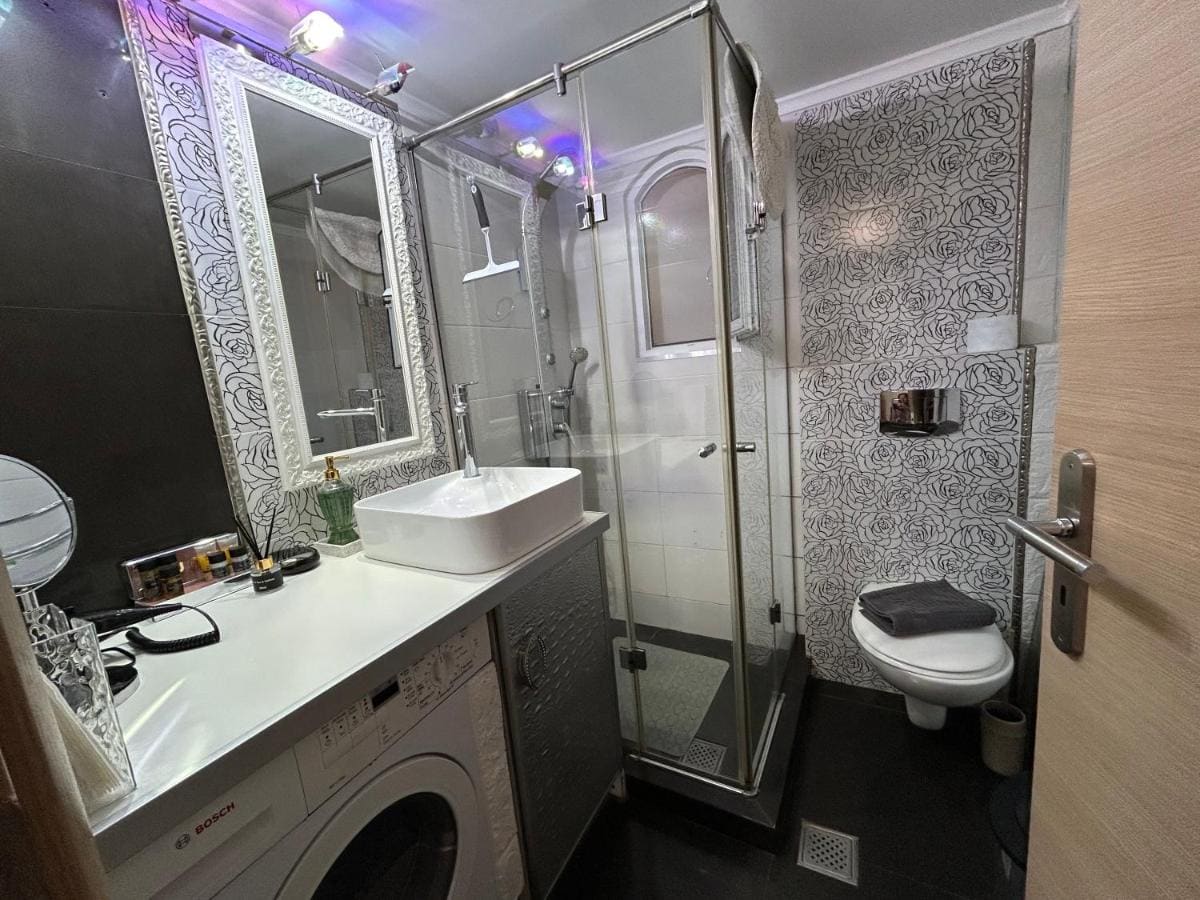Bathroom with a glass shower cabin, a vanity with mirror and a washing machine