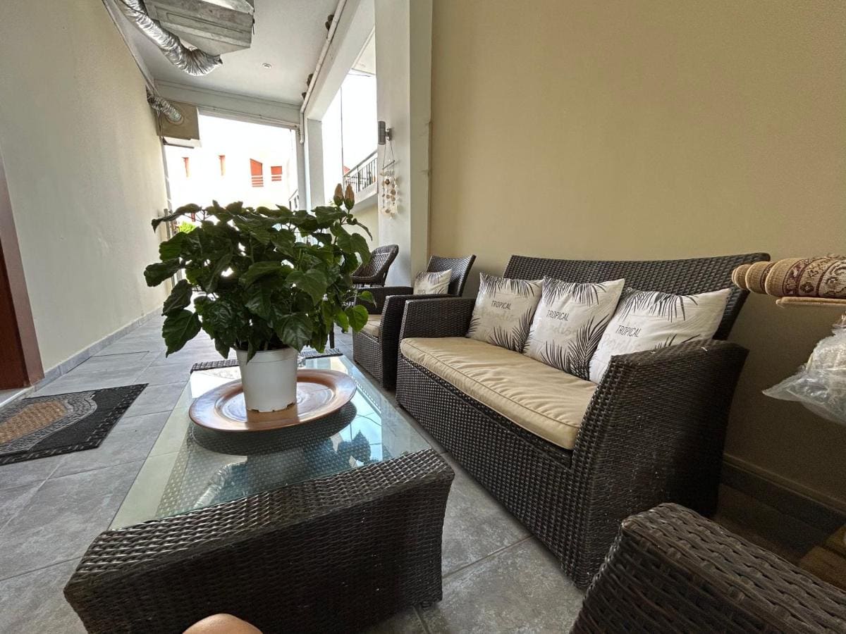 Outdoor lounge with wicker sofas and cushions around a glass table with a potted plant