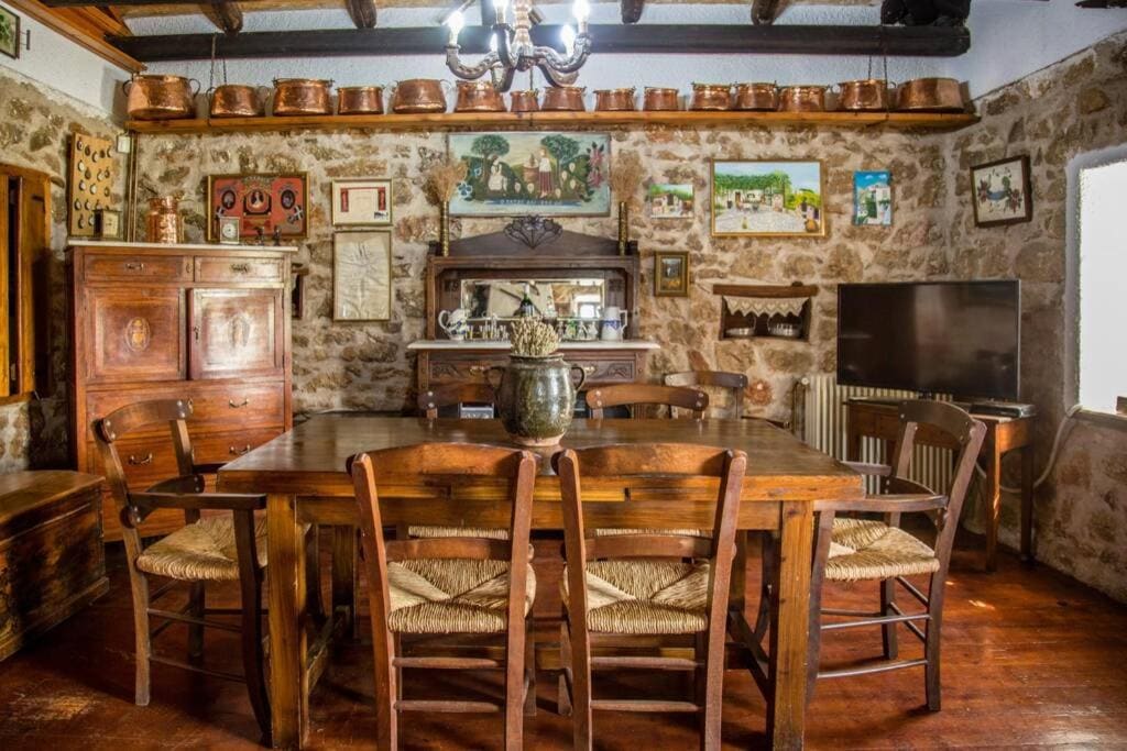 Dining room with a long wooden table and rush chairs, a carved cabinet and copper pots on the shelves