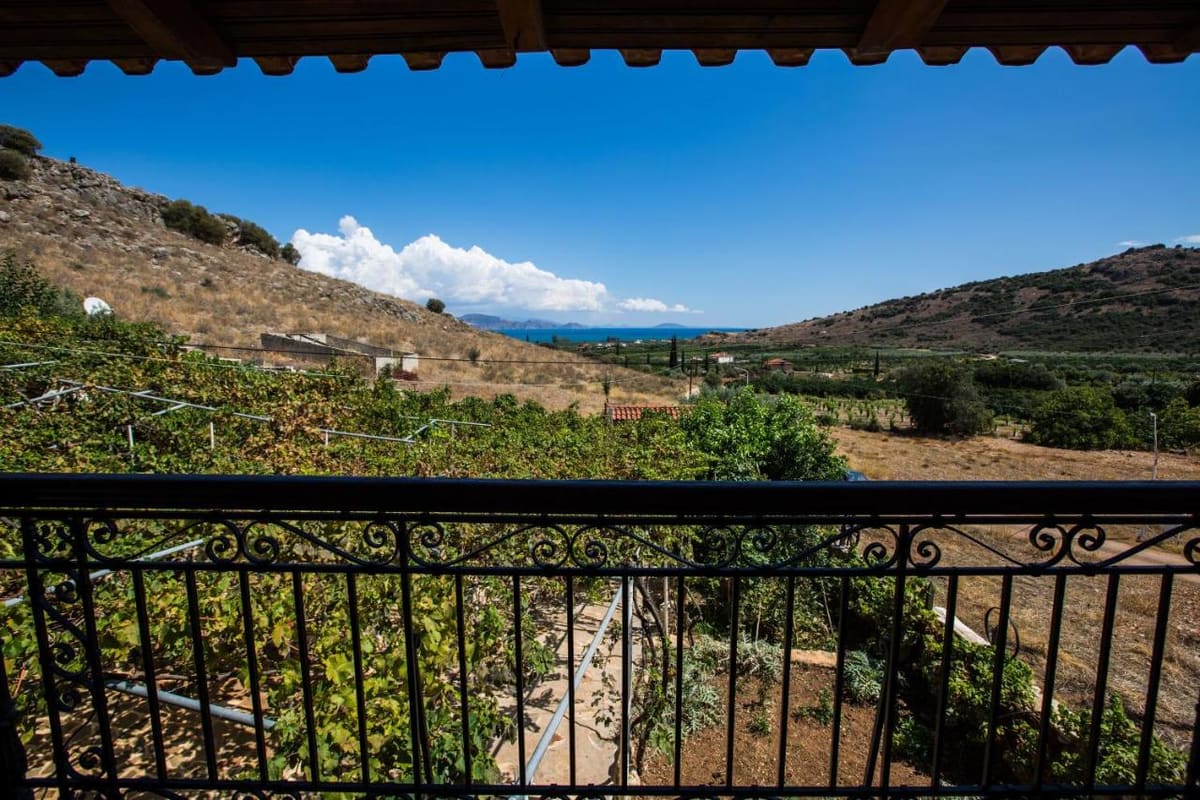 View from the covered balcony with a wrought-iron railing over the green valley and hills to the sea