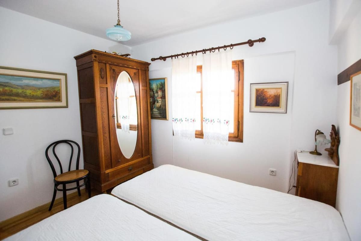Bedroom with an antique wardrobe with an oval mirror, twin beds and paintings on the walls