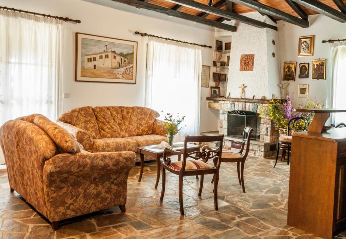 Living room with comfortable sofas, a fireplace, a stone floor, paintings and old furniture