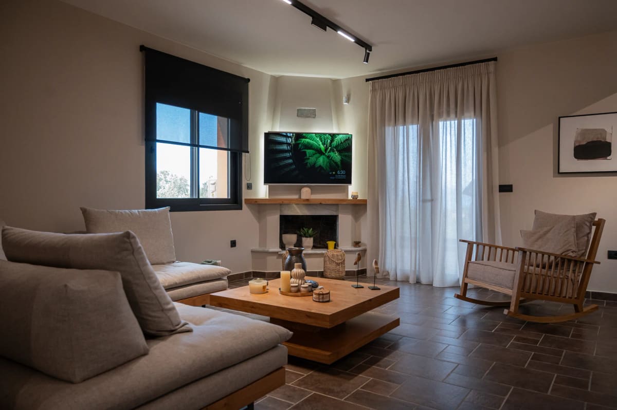 Living room with large sofas, a wooden coffee table, a corner fireplace and a rocking chair by the window