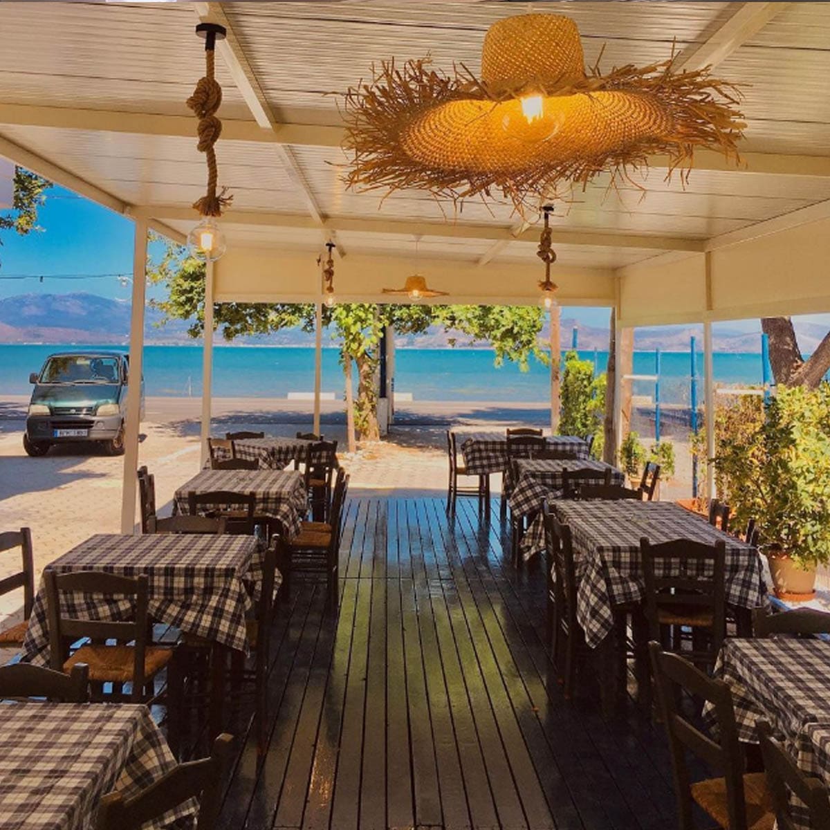 Covered taverna terrace with checked tablecloths and a view of the sea